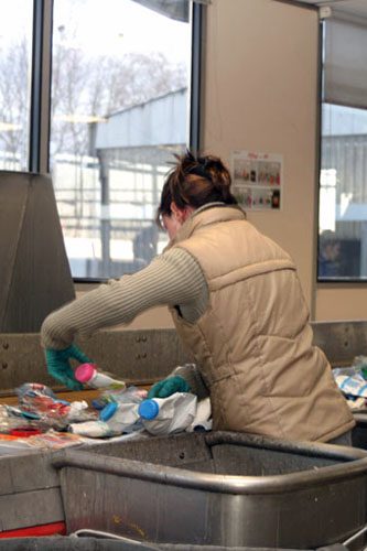 Opératrice au travail dans un centre de tri des déchets manuel.