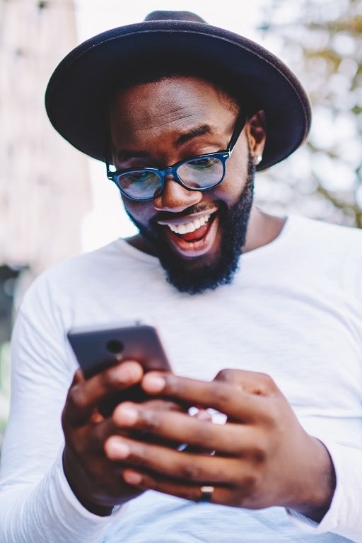 Un homme heureux de l'arrivée de la 5G à Paris rit devant son smartphone.