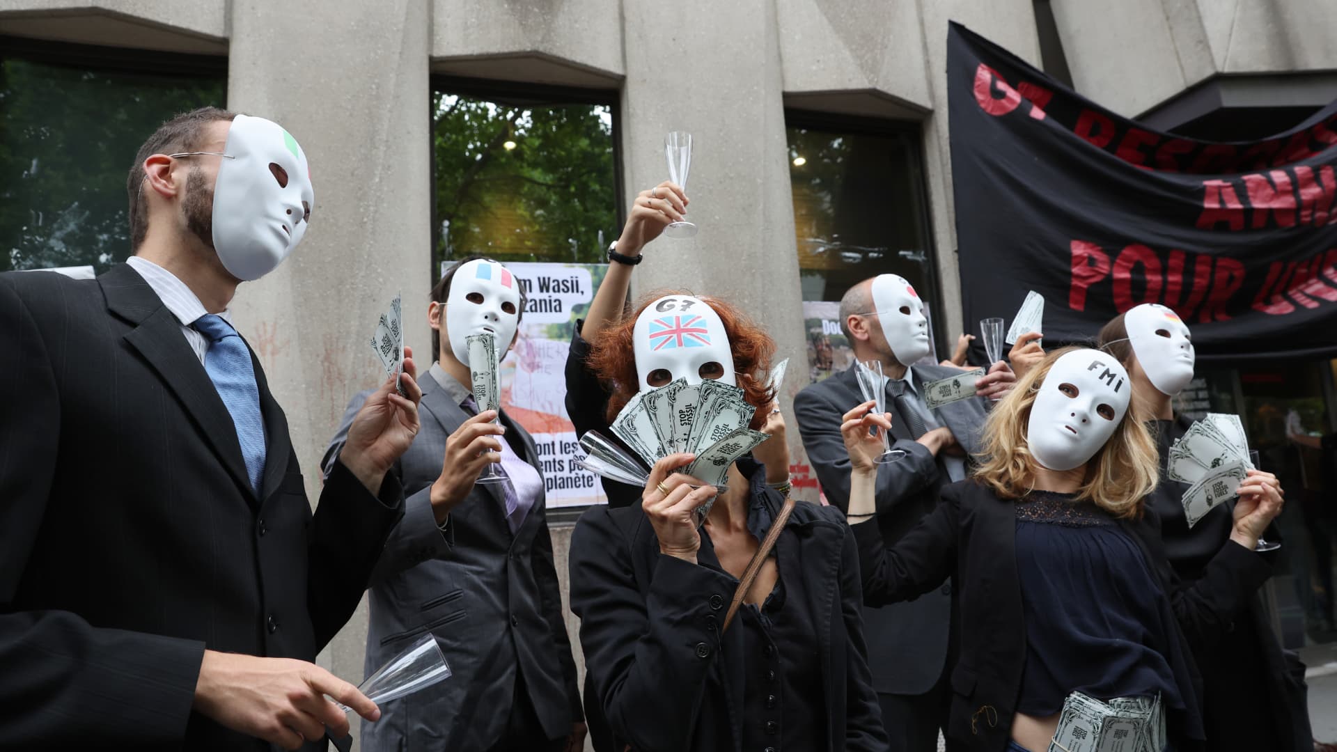 Des militants des ONG Attac, Extinction Rebellion et Youth for Climate" participent à une action dans le cadre de l'initiative "Debt for Climate", devant les locaux du FMI à Paris, le 27 juin 2022. // PHOTO : Thomas Coex / AFP